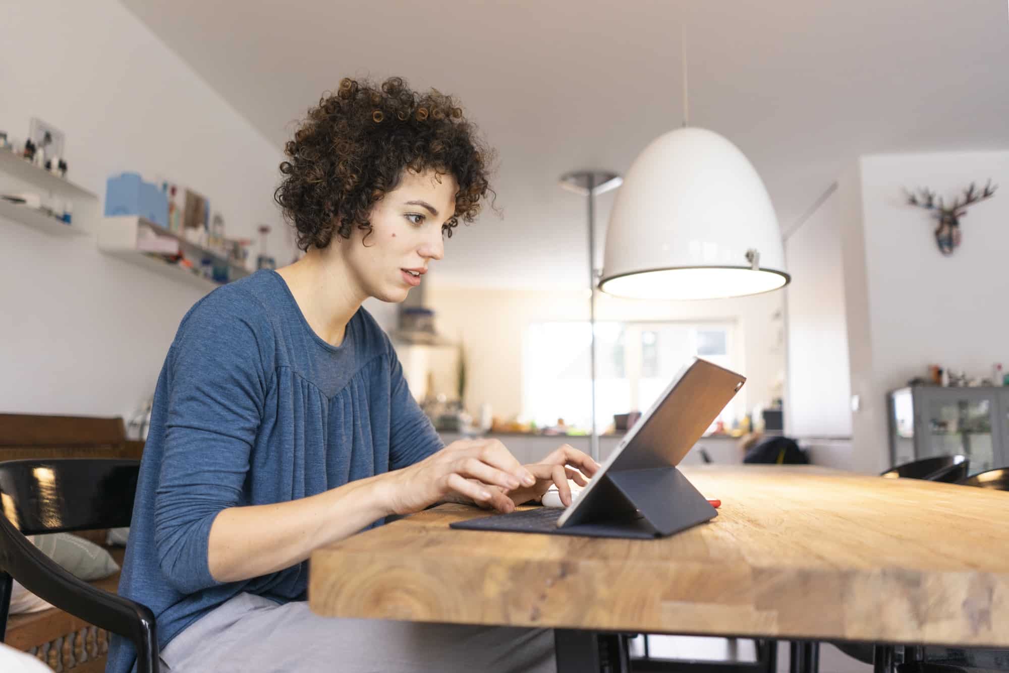 Young woman sitting at table, using digital tablet